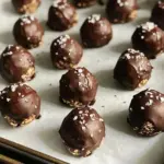 To make Dark Chocolate Sea Salt Energy Bites, you need these simple ingredients: - 1 cup rolled oats - 1/2 cup natural almond butter - 1/2 cup dark chocolate chips (70% cocoa or higher) - 1/4 cup honey or maple syrup - 1/4 cup chia seeds - 1/2 teaspoon vanilla extract - 1/2 teaspoon sea salt, plus extra for topping - Optional: 1/4 cup crushed nuts (such as almonds or walnuts) Each ingredient plays a key role in the flavor and texture. For instance, rolled oats give a hearty base, while almond butter adds creaminess and protein. Dark chocolate chips offer a rich taste, and honey or maple syrup provide sweetness. Chia seeds not only enhance nutrition but also help bind the mixture. The sea salt adds a nice contrast to the sweetness, making every bite delightful. You can also customize your energy bites by adding crushed nuts, which give a crunchy texture. Gather these ingredients before you start. You’ll see how easy it is to create a tasty and healthy snack! Start by grabbing a large bowl. Add 1 cup of rolled oats. Next, scoop in 1/2 cup of natural almond butter. Then, sprinkle in 1/2 cup of dark chocolate chips. The chocolate should be 70% cocoa or higher. Now, pour in 1/4 cup of honey or maple syrup. Add 1/4 cup of chia seeds and 1/2 teaspoon of vanilla extract. Finally, mix in 1/2 teaspoon of sea salt. Stir everything well. The mix should feel thick and sticky. If it seems too dry, add a splash more syrup or almond butter. Once your mix is ready, it’s time to roll. Take about a tablespoon of the mixture. Use your hands to shape it into a ball. Place each energy bite on a parchment-lined baking sheet. Make sure to leave some space between them. This helps them keep their shape. After rolling all the bites, sprinkle a tiny pinch of sea salt on top of each one. This adds a nice touch! Now, put the baking sheet in the freezer. Let them chill for about 30 minutes. This helps the bites firm up. Once set, move them to an airtight container. You can store these yummy bites in the fridge for a week. If you want them to last longer, keep them in the freezer for up to a month. To get the right texture, mix the ingredients well. You want a thick and sticky mix. If it feels too dry, add a little almond butter or syrup. This little change can make a big difference. Make sure to form the bites tightly so they hold together when you roll them. You can change up your bites easily. Try adding crushed nuts like almonds or walnuts for crunch. You can also mix in spices like cinnamon or nutmeg for warmth. If you love fruit, consider adding dried cranberries or raisins. This makes each bite more personal and fun. For a great presentation, place your energy bites on a nice plate. Drizzle some melted dark chocolate over the top for extra flair. You can also sprinkle more sea salt on top to enhance the flavors. These bites make a great snack at parties or a quick pick-me-up during the day. Enjoy them with friends or savor them alone! {{image_4}} You can change the nuts and seeds in this recipe. If you like peanut butter, swap the almond butter for that. You can also try sunflower seed butter for a nut-free option. For seeds, replace chia seeds with flaxseeds. They add great texture and nutrients too. Adding flavors can make your energy bites even better. Try a pinch of cinnamon for warmth. You can also use a drop of almond extract instead of vanilla. This change adds a nice twist. For a fun kick, add a dash of cayenne pepper. It gives a surprising zing! To make these bites vegan, use maple syrup instead of honey. This switch keeps them plant-based. Ensure your dark chocolate chips are dairy-free too. Many brands offer delicious vegan options. These changes make the bites suitable for everyone, while keeping that rich taste. To keep your Dark Chocolate Sea Salt Energy Bites fresh, use an airtight container. This prevents moisture and keeps them tasty. You can line the container with parchment paper for extra protection. If you stack the bites, add layers of parchment paper to avoid sticking. In the fridge, these energy bites last up to one week. Just grab one when you need a quick snack! If you freeze them, they can stay fresh for up to one month. This is great for meal prep and busy days. To thaw frozen energy bites, take them out of the freezer. Let them sit at room temperature for about 15 minutes. You can also microwave them for a few seconds if you're in a hurry. They will taste just as good as fresh! Enjoy your snack anytime. Yes, you can use other nut butters. Peanut butter, cashew butter, and sunflower seed butter work well. Just pick one that you like. Each nut butter adds a unique flavor. This lets you customize your energy bites to your taste. To make these energy bites gluten-free, use certified gluten-free oats. Most rolled oats contain gluten, so check the label. You can replace honey with maple syrup if you want. This makes them safe for gluten-sensitive folks. Yes, these energy bites are great for meal prep. They store well in the fridge or freezer. You can make a big batch and grab them as needed. They are perfect for busy days or a quick snack. You learned how to make tasty energy bites with simple ingredients. We mixed oats, almond butter, and chocolate chips for a yummy treat. I shared tips to help you get the best texture and added flavor. You can change the recipe with nuts or spices to fit your taste. Remember, store these bites well for lasting freshness. These energy bites are great for snacks or meal prep. Now, you can enjoy a healthy, fun treat anytime!