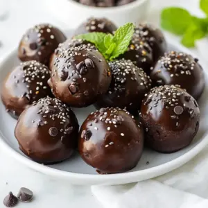 To make delicious Chocolate Mint Protein Bites, gather the following items: - 1 cup rolled oats - 1/2 cup chocolate protein powder - 1/2 cup natural nut butter (almond or peanut) - 1/4 cup honey or maple syrup - 1/4 cup dark chocolate chips - 1/4 cup fresh mint leaves, finely chopped (or 1 teaspoon peppermint extract) - 1/4 teaspoon sea salt - 2 tablespoons chia seeds (optional, for added nutrition) - 2 tablespoons unsweetened cocoa powder These ingredients are simple yet effective. Rolled oats provide a hearty base. Chocolate protein powder adds a rich flavor and boosts nutrition. Nut butter keeps the bites moist and adds healthy fats. Sweeteners like honey or maple syrup bring a touch of sweetness. Dark chocolate chips deliver indulgence and taste. Fresh mint gives a refreshing kick, while sea salt enhances all flavors. Optional chia seeds offer fiber and nutrients, making these bites even healthier. Gather these ingredients, and you&rsquo;re ready to create a tasty and nutritious snack! {{ingredient_image_2}} In a large bowl, combine: - 1 cup rolled oats - 1/2 cup chocolate protein powder - 2 tablespoons unsweetened cocoa powder Mix these dry ingredients well. Make sure there are no clumps. This mix will be the base for your tasty bites. Next, add in: - 1/2 cup natural nut butter (like almond or peanut) - 1/4 cup honey or maple syrup - 1/4 teaspoon sea salt Stir these wet ingredients into the dry ones. Mix until the blend is sticky and smooth. This step helps everything hold together. Now, fold in: - 1/4 cup dark chocolate chips - 1/4 cup fresh mint leaves, finely chopped (or 1 teaspoon peppermint extract) - 2 tablespoons chia seeds (optional) Gently mix these in until they spread evenly throughout. The mint adds a fresh taste, while chocolate chips bring sweetness. Cover the bowl with plastic wrap and refrigerate for about 15-20 minutes. This helps the mixture firm up. After chilling, scoop out tablespoon-sized portions. Roll them between your palms to create small balls. Place the formed bites on a plate or baking sheet lined with parchment paper. Make sure they are spaced out. Return them to the fridge for another 30 minutes. This will set them fully and enhance their flavors. To keep your chocolate mint protein bites fresh, store them in an airtight container. A fridge is the best place for these bites. They can last up to a week this way. For longer storage, you can freeze them. Just place them in a freezer-safe bag. They will stay fresh for up to three months. Serving these bites can be fun and creative. Place them in a pretty jar or a decorative bowl. This makes a great treat for guests. You can also serve them with fresh fruit. A side of berries adds color and a fresh taste. For a special touch, add a mint sprig on top. It looks nice and smells great too! You can change the flavor of these bites easily. Try swapping the nut butter for sunflower seed butter for a nut-free option. You can also use different sweeteners like agave syrup. For a different taste, add spices like cinnamon or vanilla extract. If you want extra crunch, toss in some chopped nuts or seeds. The options are endless! Pro Tips Chill for Better Texture: Allow the mixture to chill for a bit longer if you find it too sticky to handle, this will help in forming smooth bites. Customize Your Sweetness: Adjust the amount of honey or maple syrup based on your personal taste preference; you can also use a sugar substitute for a lower-calorie version. Experiment with Flavors: Try adding different extracts like vanilla or almond, or mix in other ingredients like dried fruits or nuts for a unique twist. Perfect for Meal Prep: These protein bites can be stored in an airtight container in the fridge for up to a week, making them a great on-the-go snack! {{image_4}} Chocolate mint protein bites pack a powerful punch of nutrients. Each bite offers a blend of protein, fiber, and healthy fats. Key nutrients include: - Rolled oats: Great source of whole grains. They provide fiber to help digestion. - Chocolate protein powder: Adds protein, which helps with muscle repair and keeps you feeling full. - Nut butter: Supplies healthy fats and protein, fueling your body. - Honey or maple syrup: Natural sweeteners that give energy and flavor. - Dark chocolate chips: A treat that also brings antioxidants to the mix. - Fresh mint: Offers a refreshing taste and may aid digestion. - Chia seeds (if included): Packed with omega-3s and more fiber. Incorporating these ingredients makes a healthy snack. Nuts and seeds provide protein and healthy fats. They help you stay full and support brain health. Protein powders boost muscle growth and recovery. Oats are great for heart health. They lower cholesterol and keep your heart healthy. Dark chocolate has antioxidants, which are good for the heart too. Mint can help with digestion and freshen your breath. These bites fit many diets. You can easily make them vegan by using maple syrup and a plant-based protein powder. They are also gluten-free when you choose certified gluten-free oats. This snack suits many dietary needs while still being tasty. Enjoy these bites as a guilt-free treat that supports your health goals! To switch up the taste of your protein bites, try using different ingredients. For example, you can replace the chocolate protein powder with vanilla protein powder for a lighter flavor. If you love peanut butter, swap out the nut butter for peanut butter. This gives you a rich, nutty flavor. You can also mix in other add-ins like dried fruits or seeds to create unique bites. Think about adding coconut flakes for a tropical twist or some spices like cinnamon for warmth. Each change can bring a new experience. If you&rsquo;re short on time, store-bought protein bites can be a great option. Many brands offer tasty choices. Look for brands like RXBAR or L&Auml;RABAR. These often have simple, whole ingredients and come in various flavors. Check the labels to find bites that suit your taste and dietary needs. They can save you time while still providing a healthy snack. But remember, making your own gives you more control over the ingredients. You can also adapt your protein bites for the seasons. During fall, add pumpkin spice to your mix for a cozy flavor. In winter, consider using peppermint extract to bring a festive touch. For summer, you could add fresh berries for a bright, fruity taste. Using seasonal ingredients not only keeps things fresh but also connects you with the time of year. Enjoy exploring these variations to keep your snacks exciting! To make these protein bites vegan, you can swap the honey for maple syrup. Use a plant-based nut butter like almond or peanut. Ensure the chocolate chips are dairy-free. You can also skip the chia seeds if you prefer. These changes keep the bites tasty and vegan-friendly. Yes, you can freeze these protein bites. Place them in an airtight container or a freezer-safe bag. Make sure to separate layers with parchment paper. To thaw, leave them in the fridge overnight or at room temperature for about 30 minutes. They will taste great after freezing! You can use protein bites as a quick breakfast. They also work well as a post-workout snack. Try adding them to your smoothie bowl for extra flavor. You can even crumble them over yogurt for a tasty treat. They are versatile and fit into many meals! These protein bites last about one week in the fridge. Store them in an airtight container to keep them fresh. Check for any off smells or changes in texture. If they seem dry or hard, it&rsquo;s best to toss them out. Enjoy them while they&rsquo;re fresh! These chocolate mint protein bites are tasty and healthy. We covered the simple ingredients, step-by-step instructions, and ways to customize your bites. You can store them, serve creatively, and even try seasonal variations. These bites fit various diets and offer excellent nutrition. Enjoy making these bites your own while boosting your energy. With a little practice and creativity, you&rsquo;ll have a fun, healthy snack any time!
